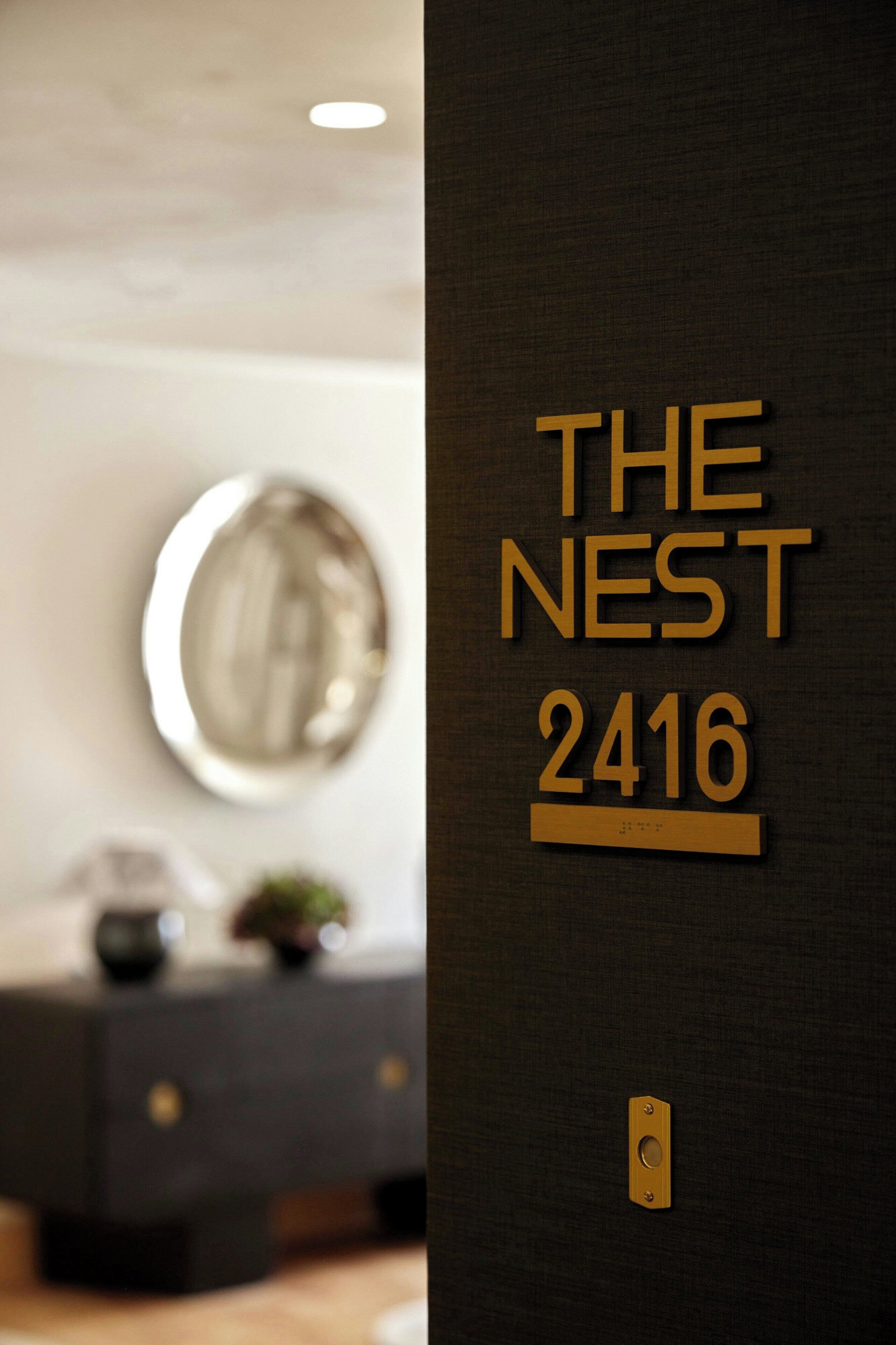 A wall with the text "THE NEST 2416" indicating a hotel or property name and number.