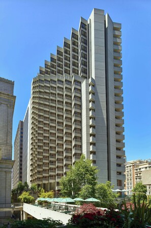 Surrounded by lush greenery, this high-rise building offers a tranquil retreat with outdoor seating areas and balconies on each floor.