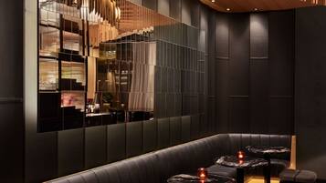 A modern interior with a curved wooden ceiling, black leather seating, and marble-topped tables.