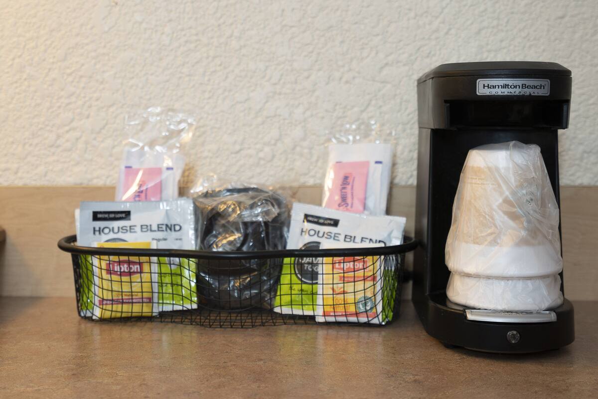A coffee maker and a basket of coffee pods on a countertop.