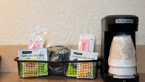 Una cafetera y un cesto con bolsitas de té sobre una encimera.