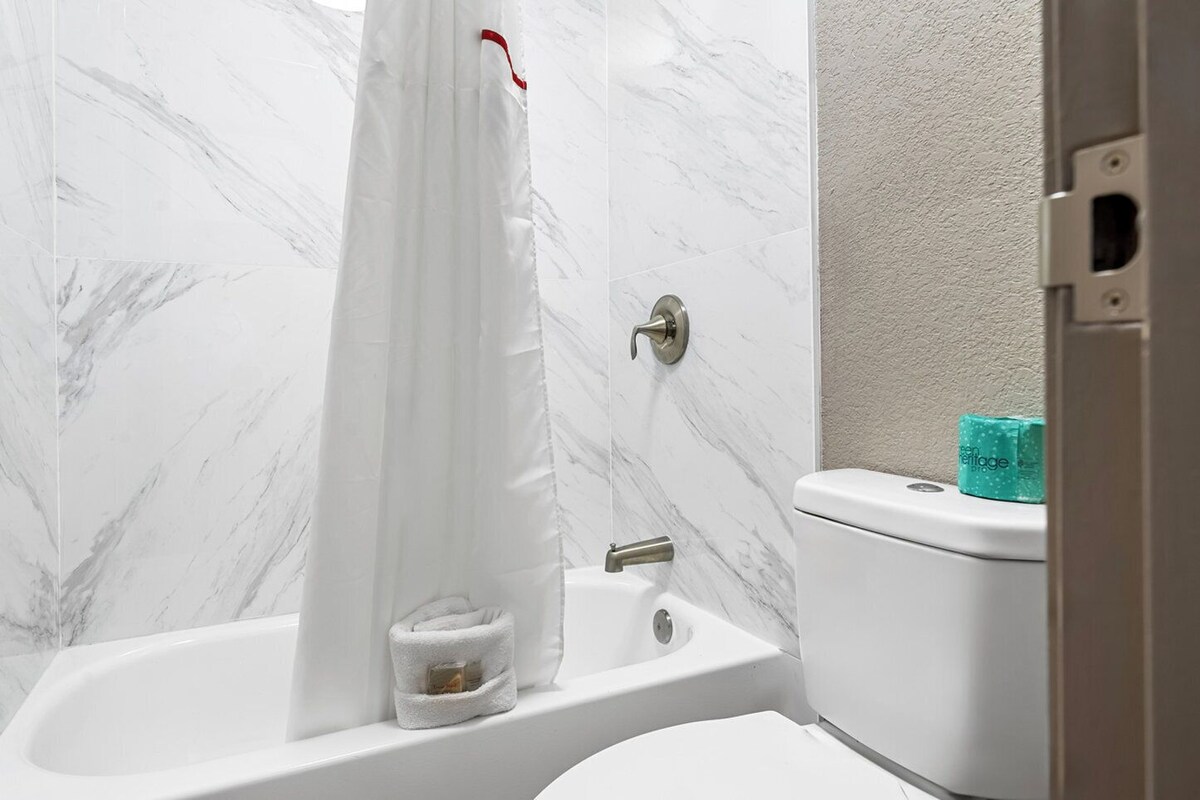 Un baño con bañera, inodoro y cortina de ducha.