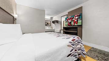 Habitación de hotel con cama, televisión, escritorio y baño a la vista.