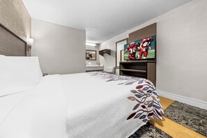 Habitació d'hotel amb un llit, una televisió, un escriptori i un bany visible al fons.
