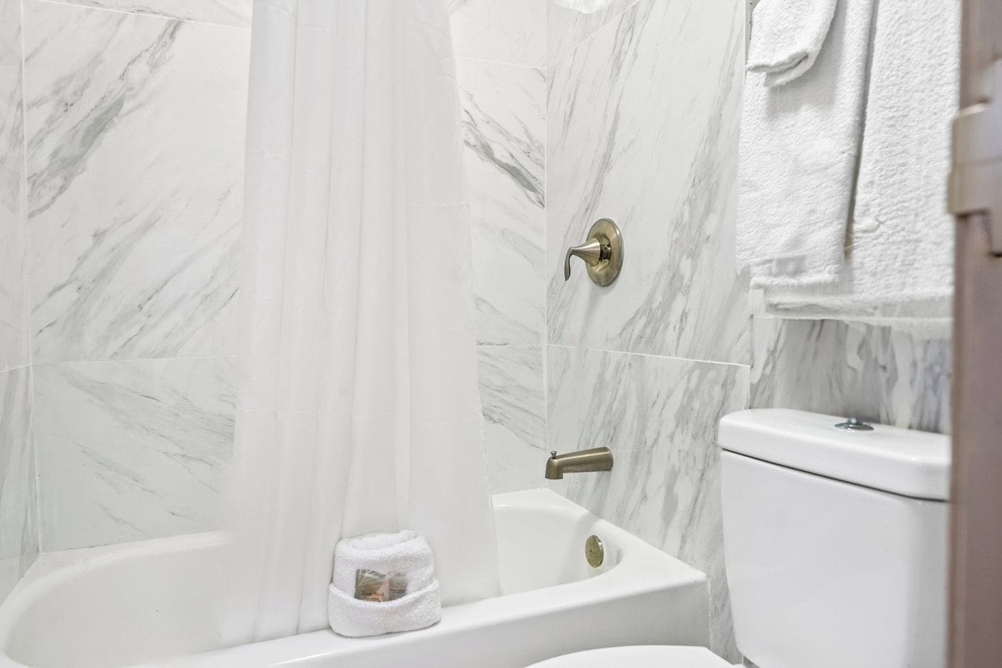 A bathroom with a bathtub, toilet, and a shower curtain.