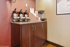 A coffee station with hot water dispensers, a coffee machine, and a paper towel dispenser.