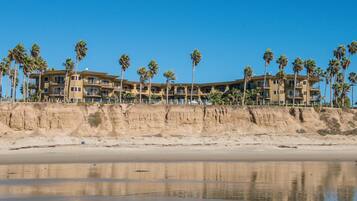 Un hotel con diversi balconi, palme e vista sulla spiaggia.