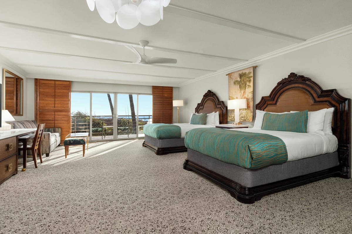 A hotel room with two beds, a desk, and a chair.