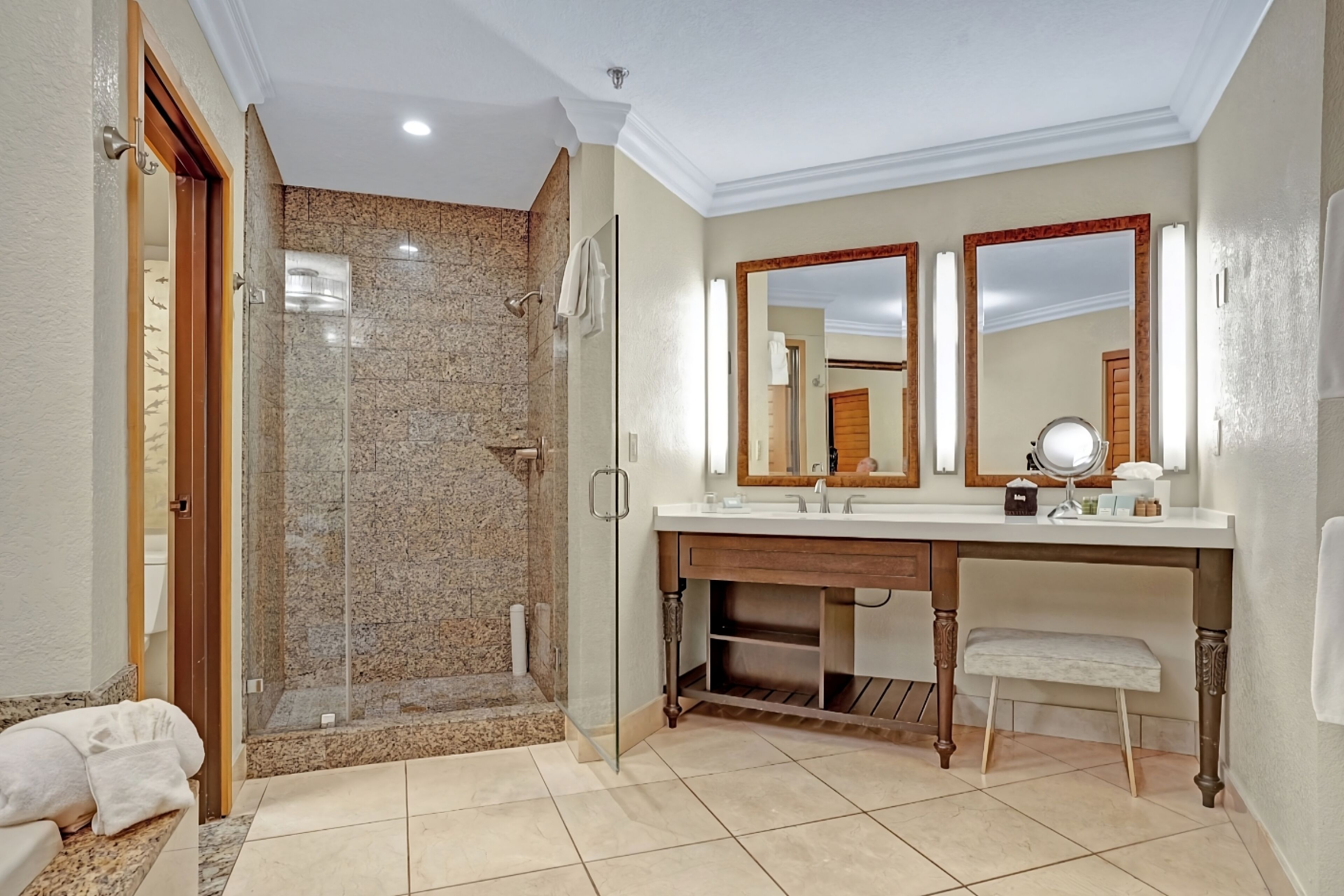 Une salle de bain moderne avec une douche à parois de verre, un meuble-lavabo doté de deux miroirs et un banc.