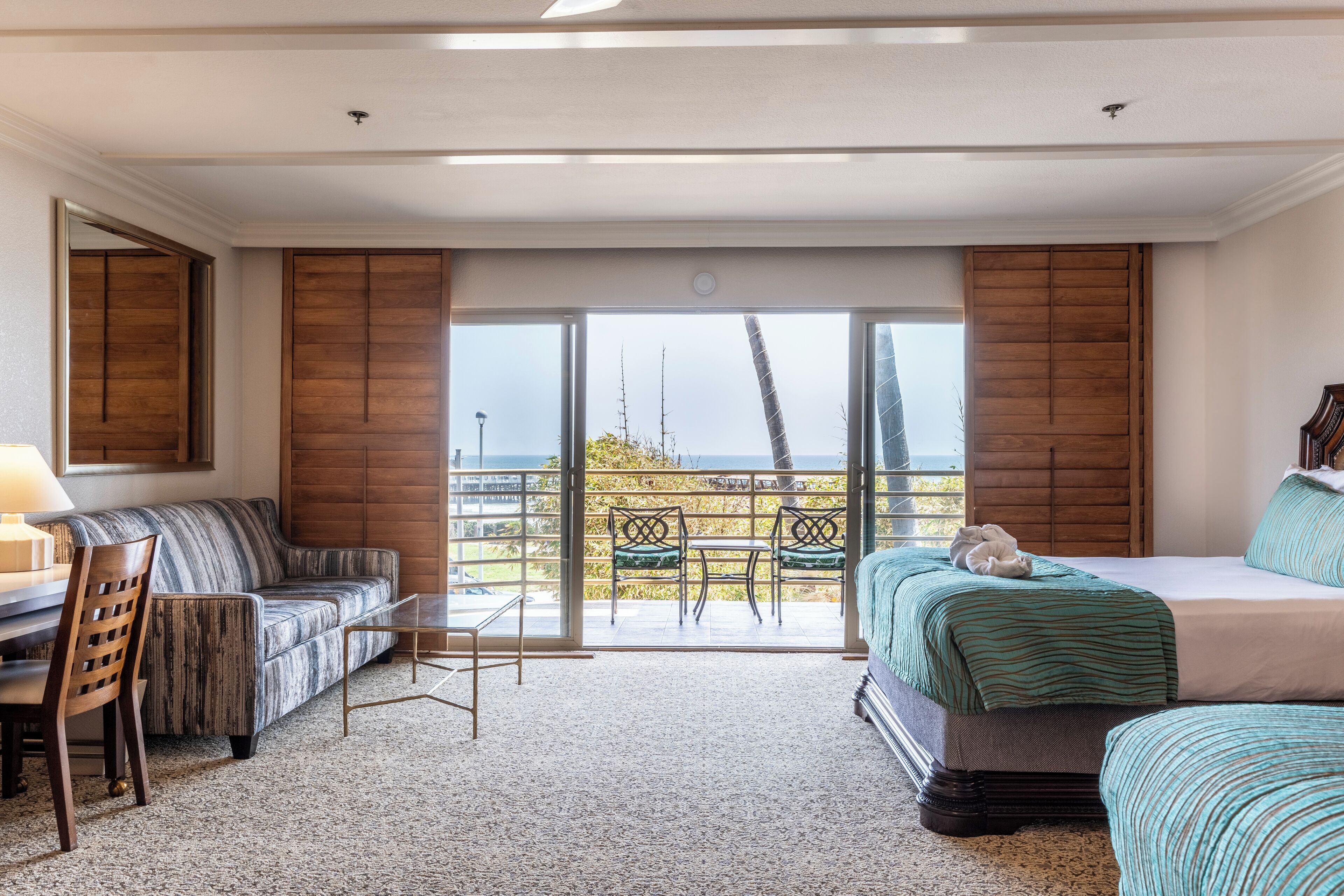 Habitación de hotel con balcón, sofá, cama, mesa y una silla.