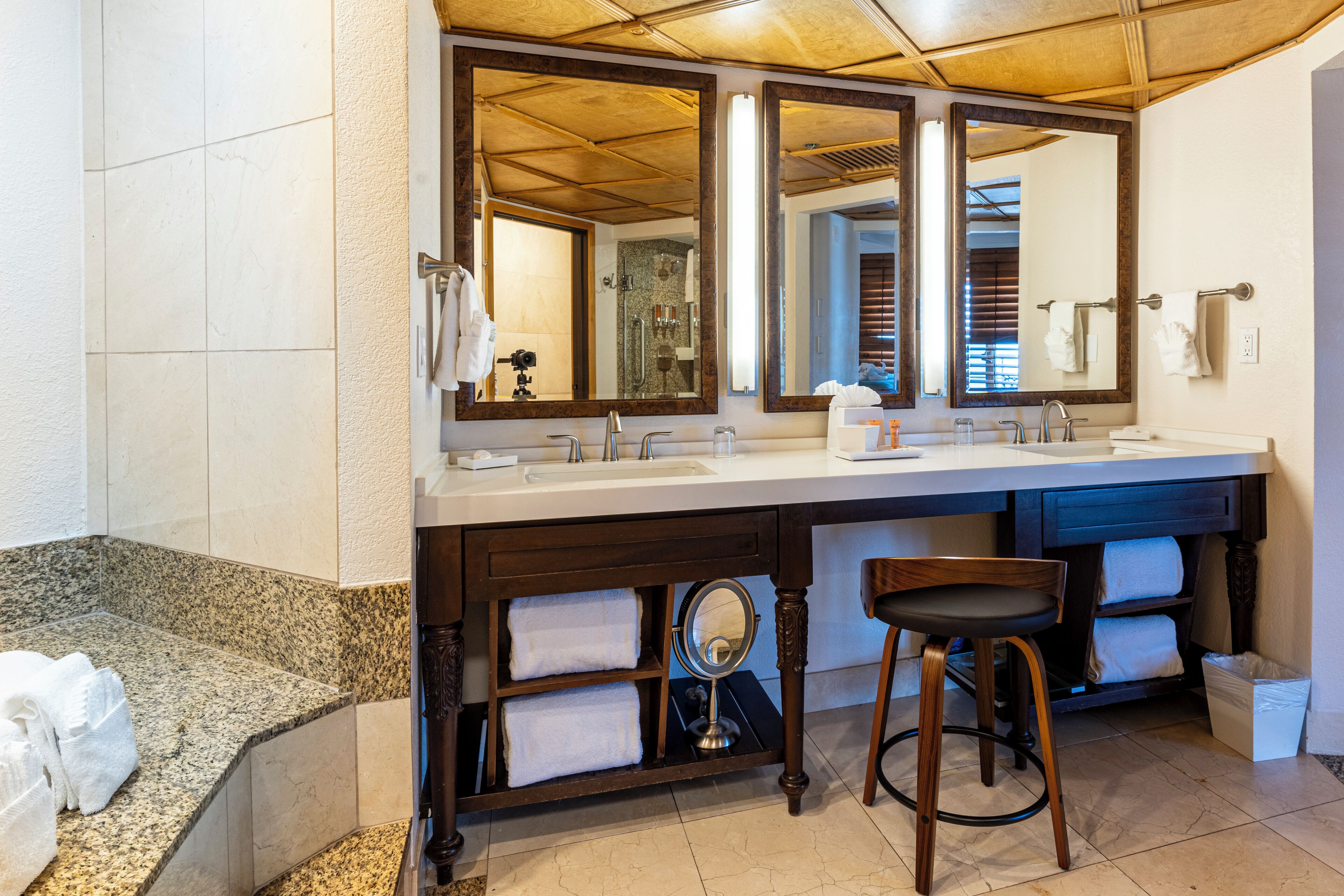 Une salle de bain avec deux éviers, de grands miroirs, une baignoire et un meuble-lavabo avec des serviettes.