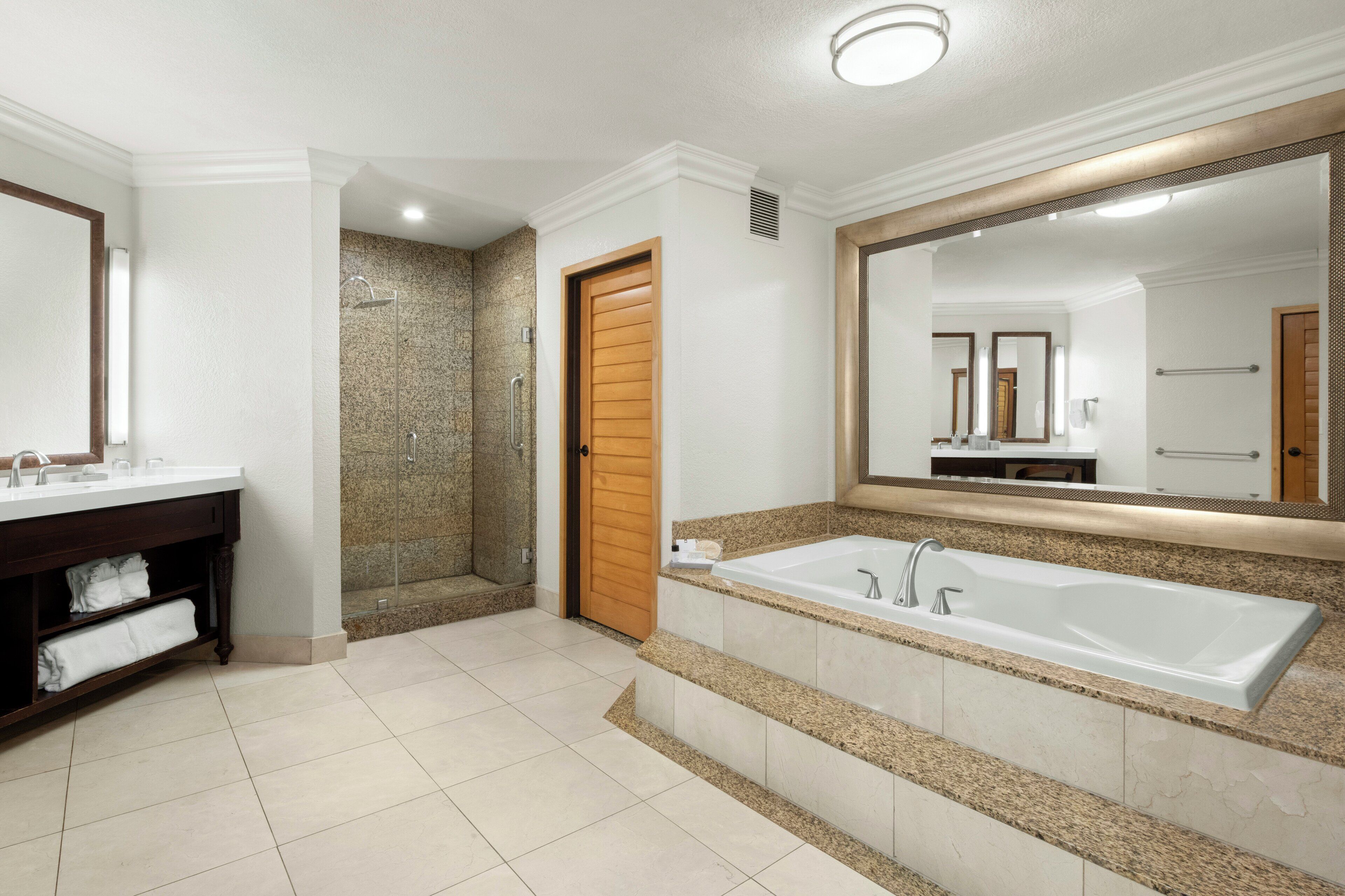 Un baño moderno con una bañera grande, una zona de ducha separada y un lavamanos con espejo.