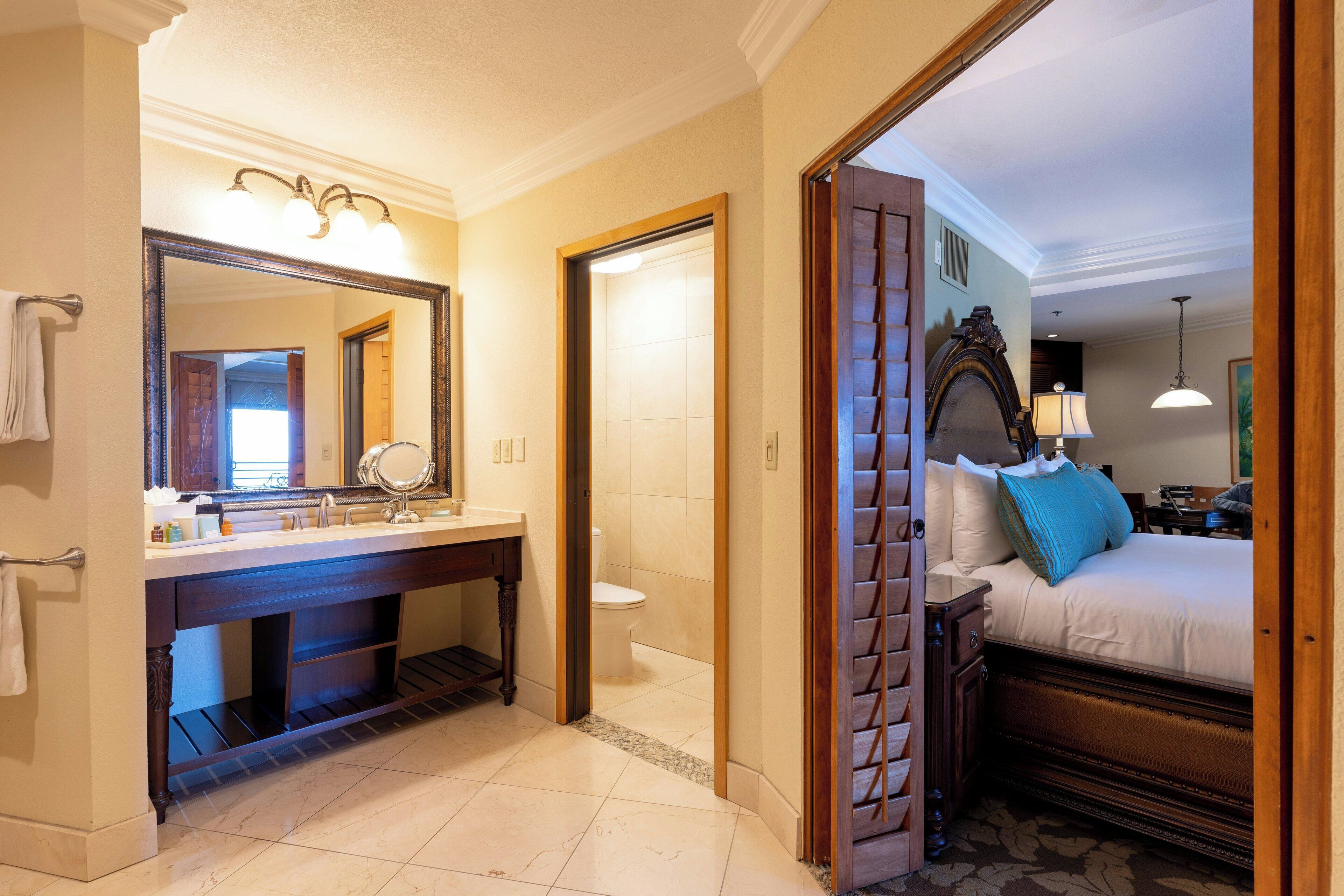 A hotel bathroom with a large mirror, sink, and toilet.