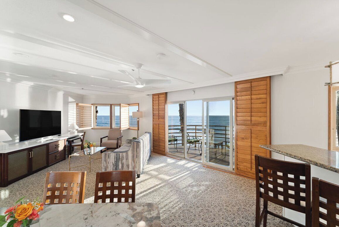 Una sala de estar moderna con televisión, asientos y vista al mar.