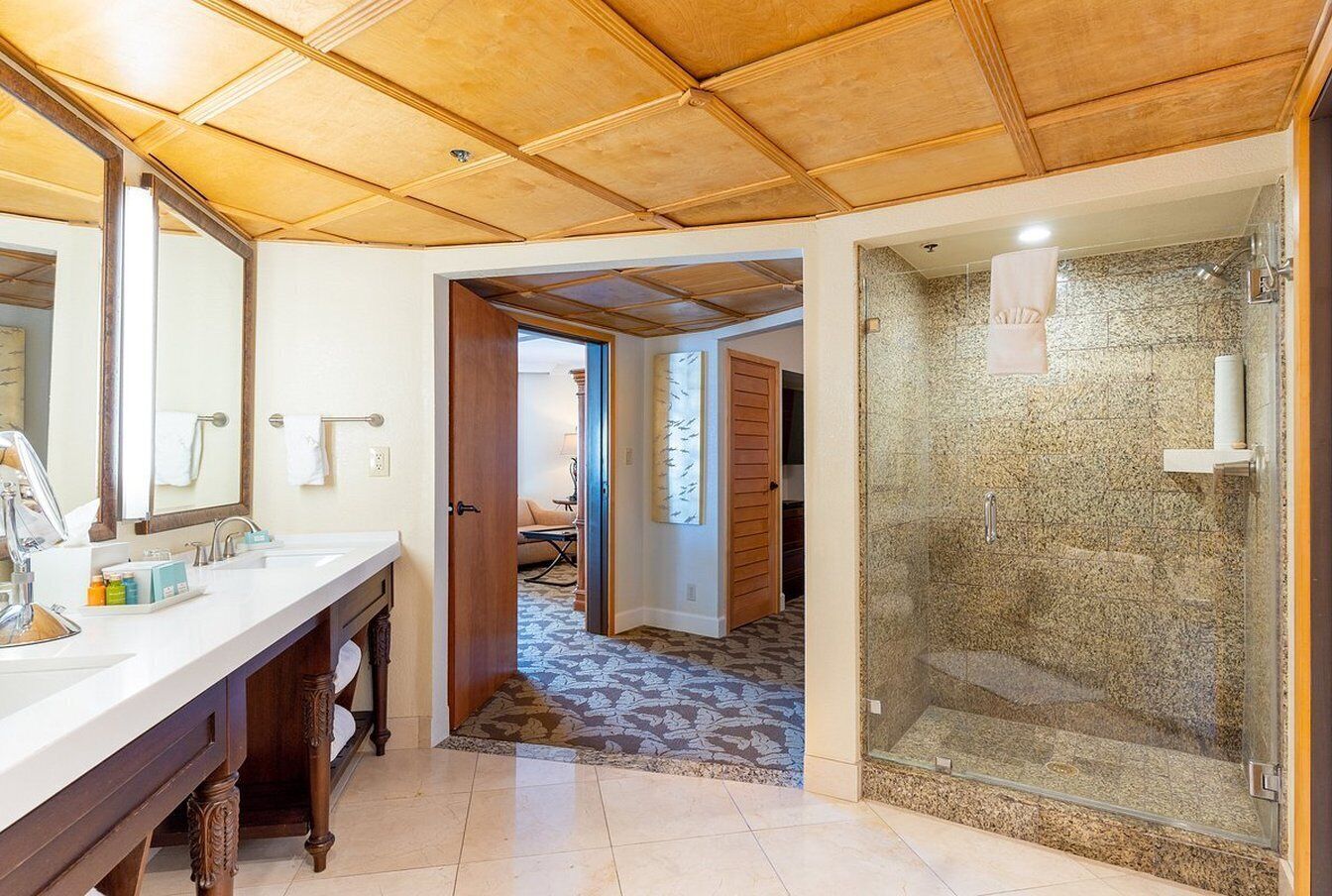 A bathroom with a wooden ceiling, a glass shower enclosure, and a white sink with a mirror.