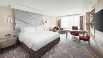 A modern hotel room with a large bed, a desk, and a chair.