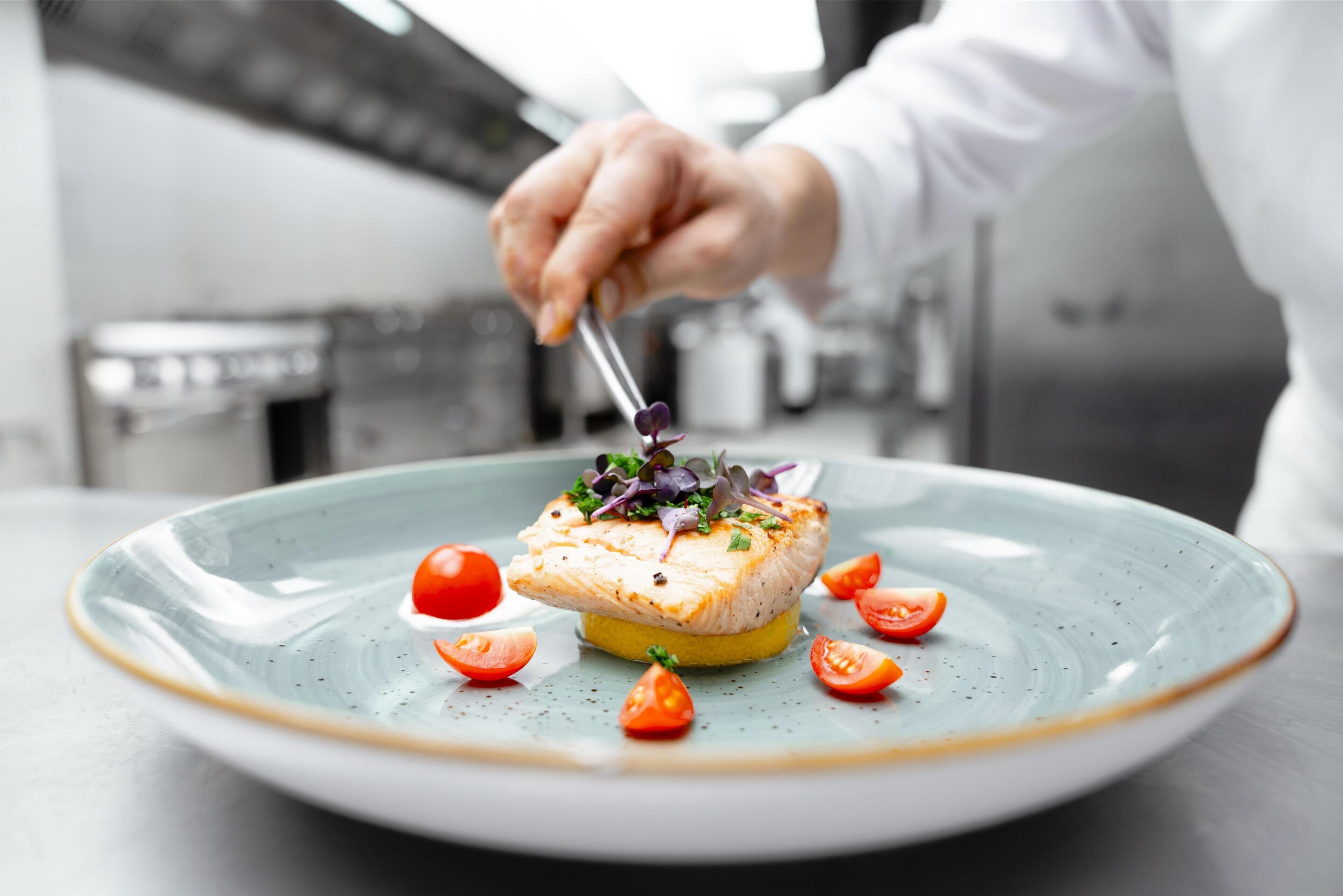 A chef preparing a dish on a plate with a fork.
