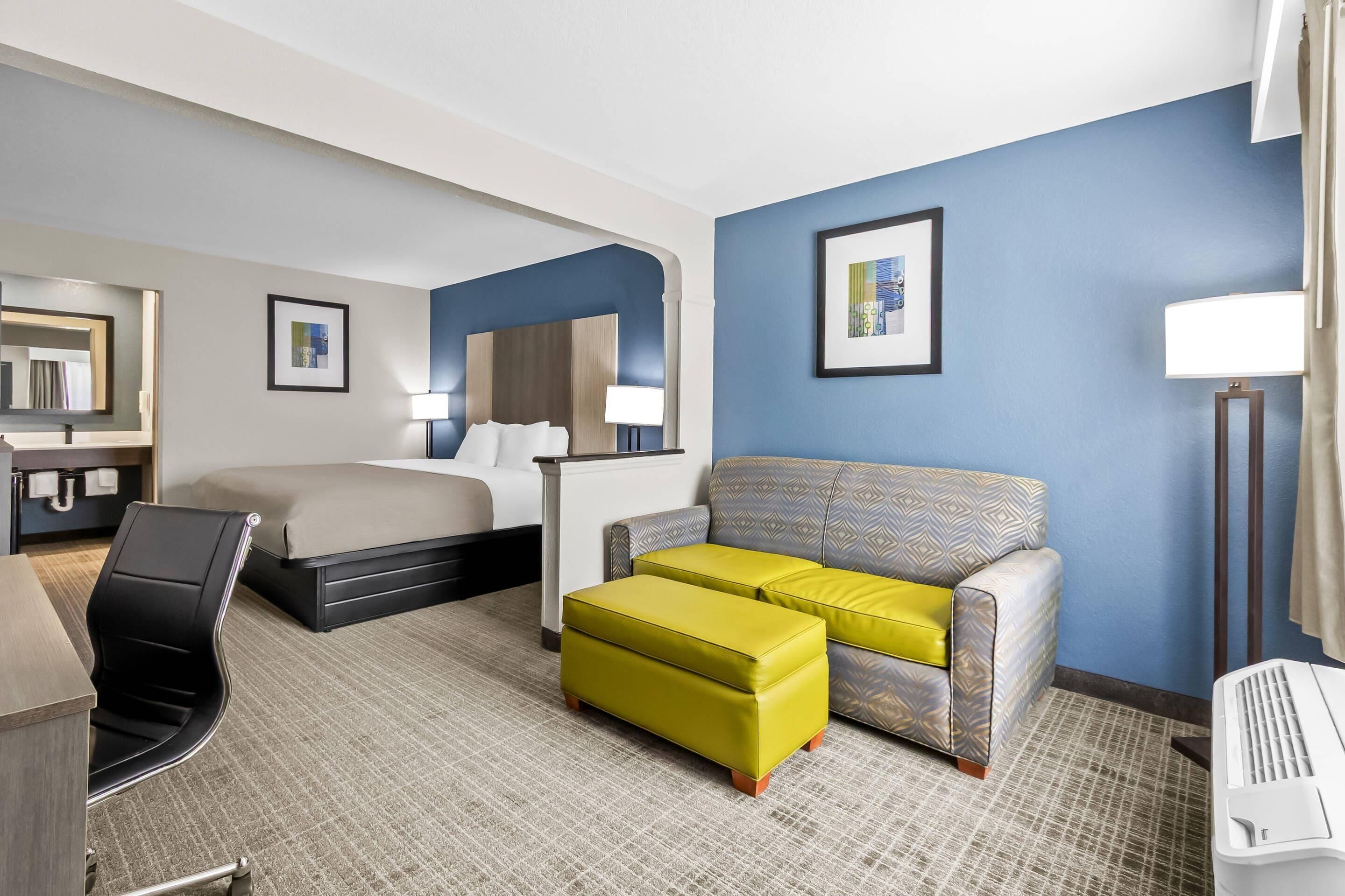 A hotel room with a bed, a sofa, a desk, and a chair.