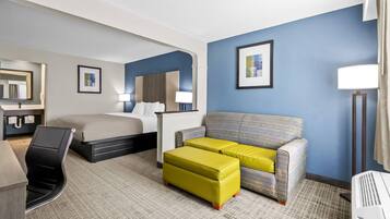 Una habitación de hotel con cama, sofá, escritorio y una silla.
