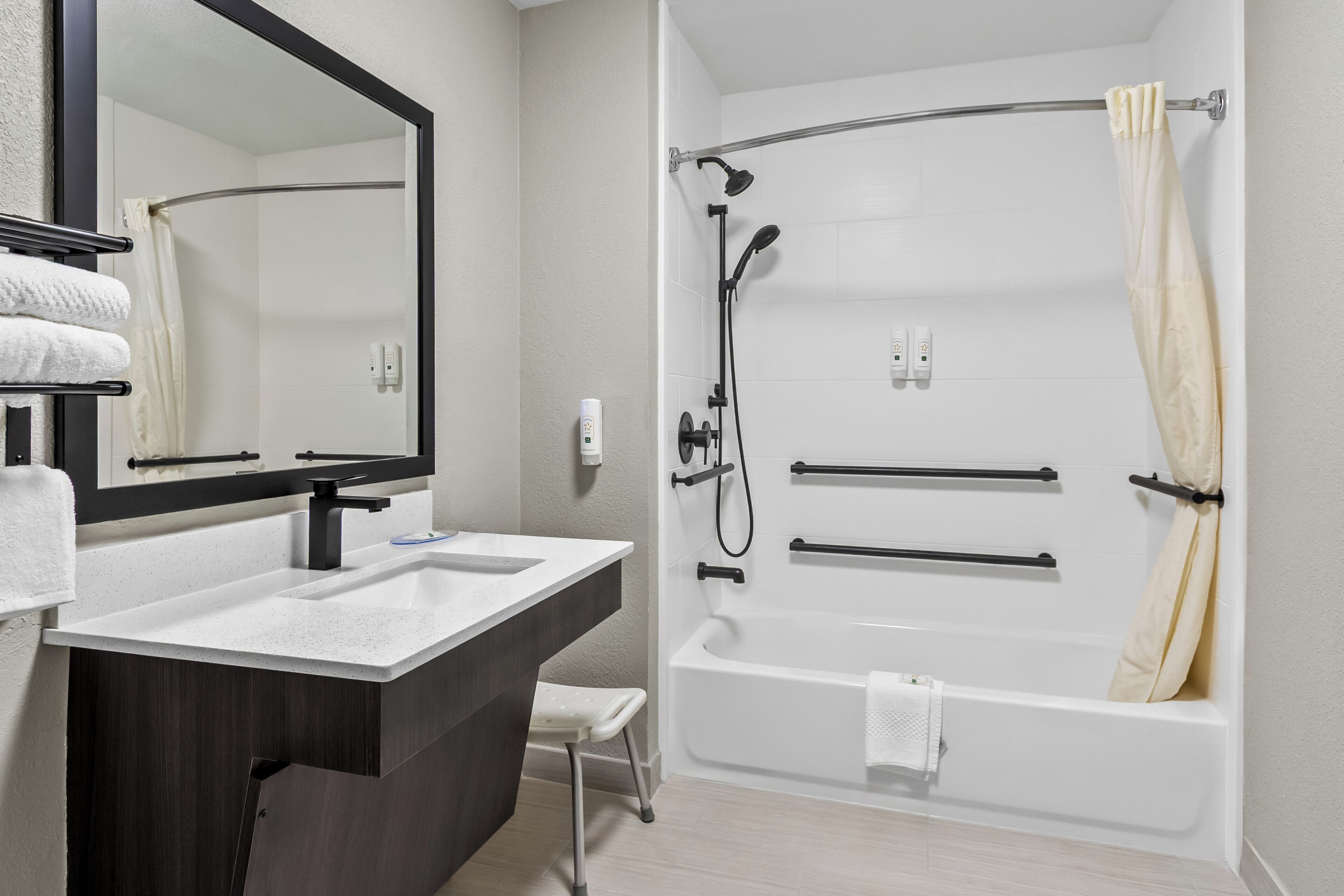 A modern bathroom with a sink, mirror, and bathtub.