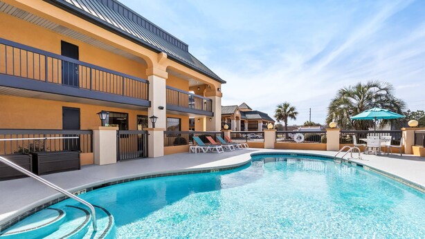 A swimming pool with lounge chairs and a building with balconies. - Quality Inn & Suites Florence Civic Center (Florence)