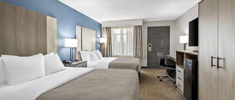 A hotel room with two beds, a desk, a TV, and a wardrobe.