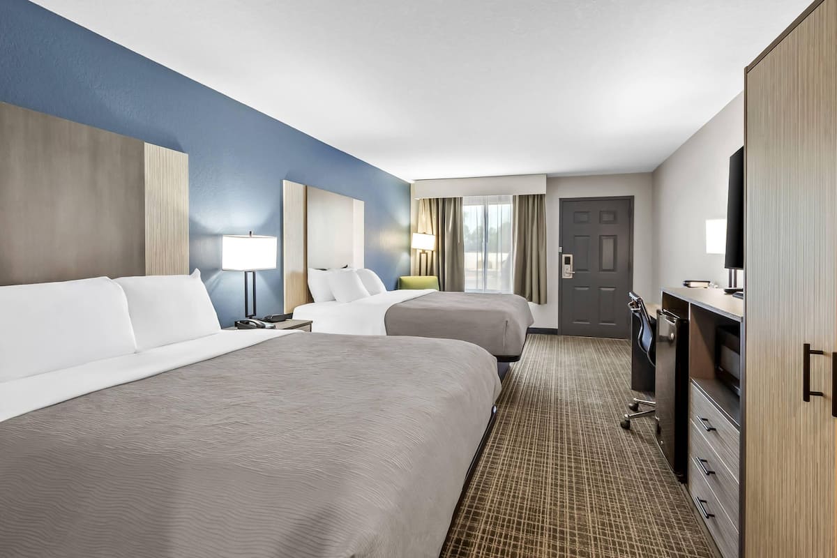 A hotel room with two beds, a desk, a TV, and a wardrobe.