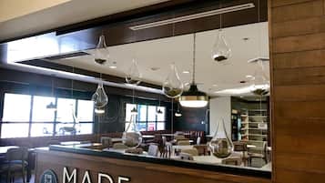 A restaurant interior with a wooden counter, hanging pendant lights, and a large mirror reflecting the dining area.