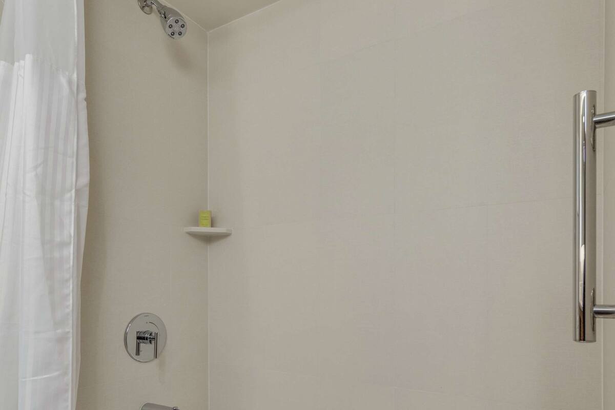 A modern bathroom with a white bathtub, a showerhead, and a towel rack.