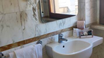 Une salle de bain avec un lavabo blanc, un miroir, un porte-serviettes et une poubelle.