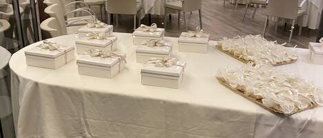 A banquet hall with round tables set for a formal event, featuring white tablecloths and neatly arranged centerpieces.