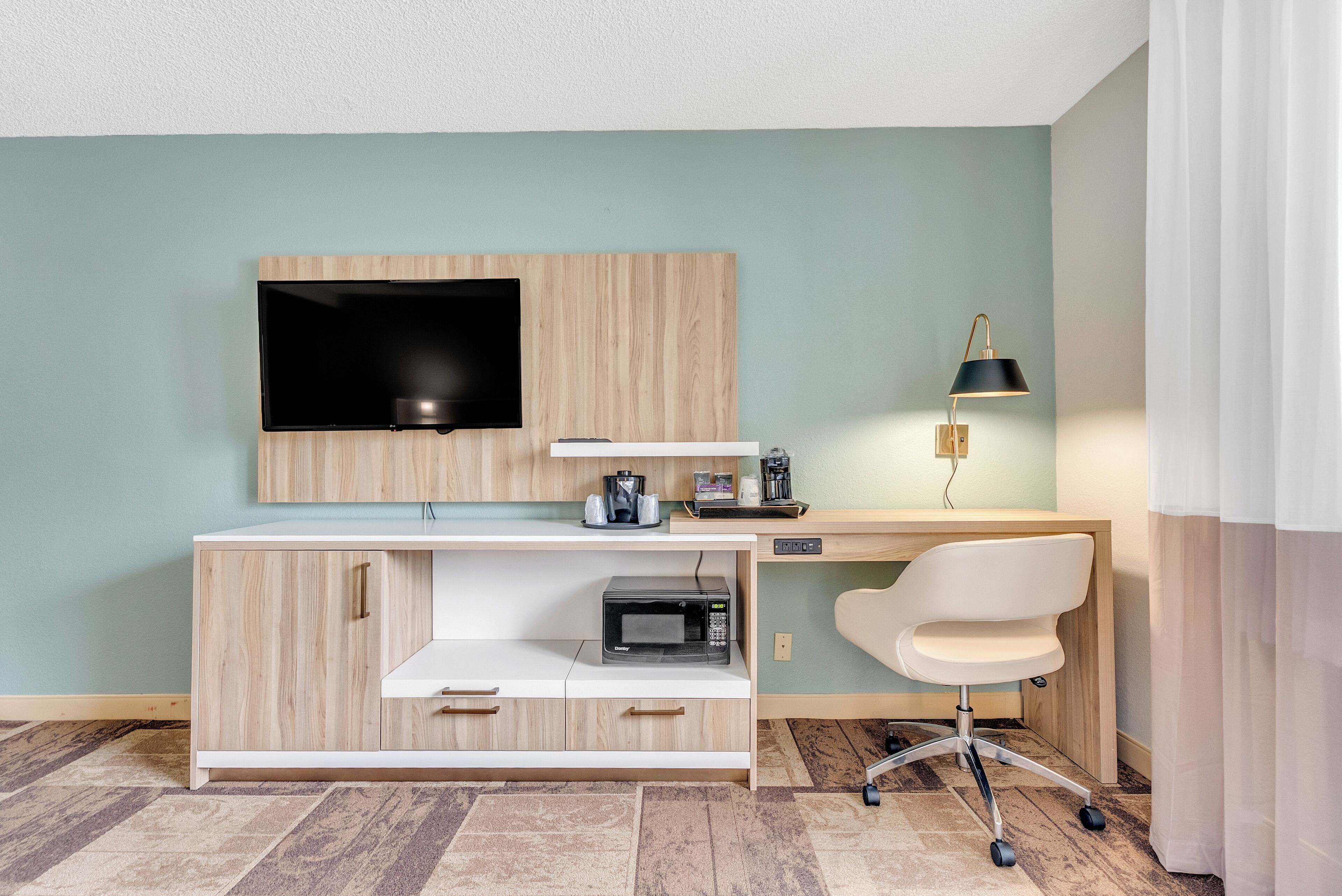 Ein modernes Zimmer mit einem Holztisch, einem Flachbildfernseher, einer Lampe und einer Mikrowelle.