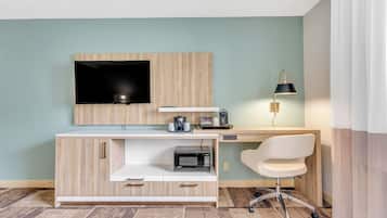 Ein modernes Zimmer mit einem Holztisch, einem Flachbildfernseher, einer Lampe und einer Mikrowelle.