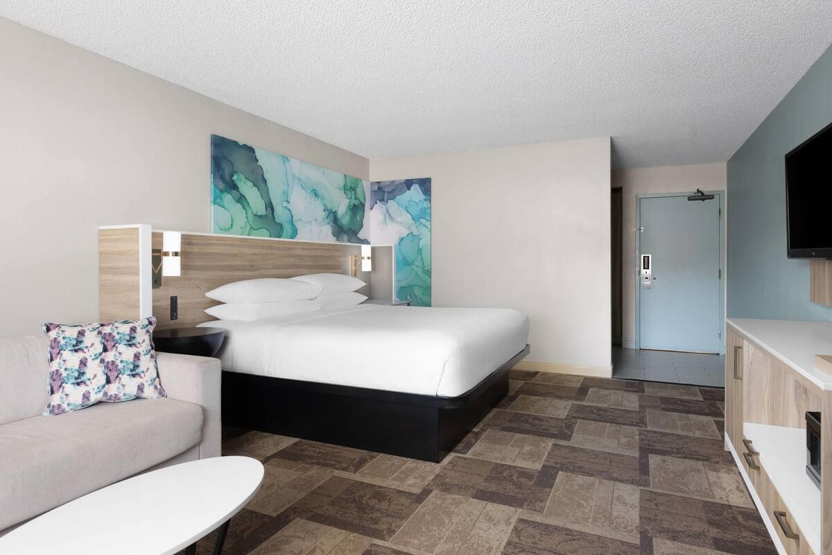 Ein Hotelzimmer mit einem Bett, einer Couch, einem Fernseher und einer Tür.