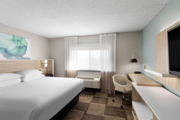 A hotel room with a bed, desk, chair, and a large TV. - Wyndham Garden Newark/Fremont Silicon Valley (Newark)