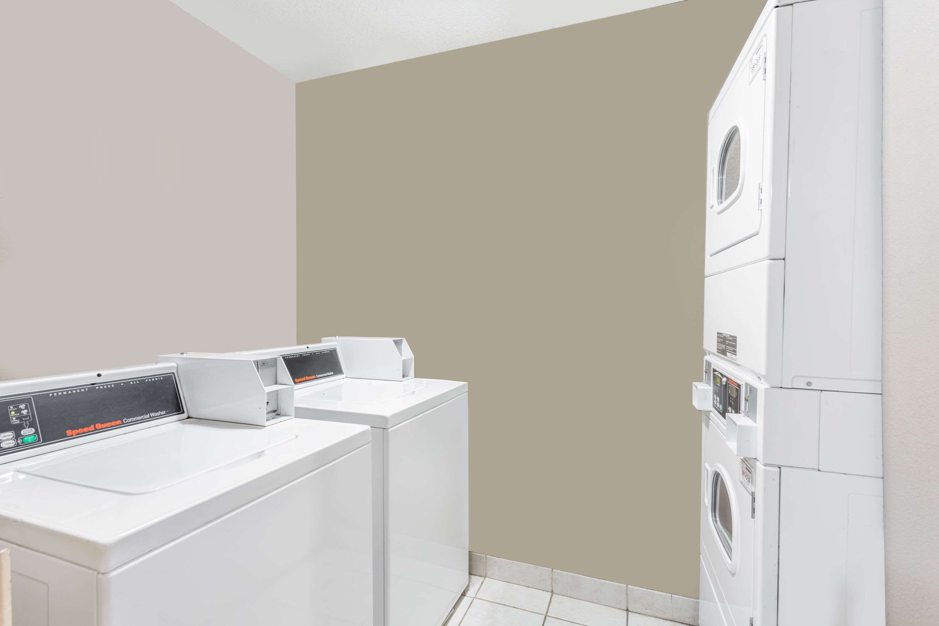 A laundry room with two front-loading washing machines and a stacked dryer.