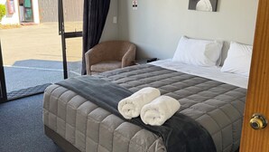 Una habitación de hotel con una cama, una silla, un cuadro y un equipo de aire acondicionado.