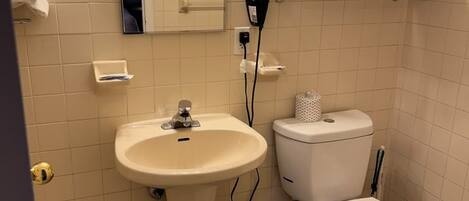 A bathroom with a sink, toilet, and a mirror above the sink.