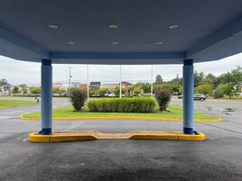 A covered outdoor area with a blue canopy, yellow curb, and a view of a Starbucks building in the background.