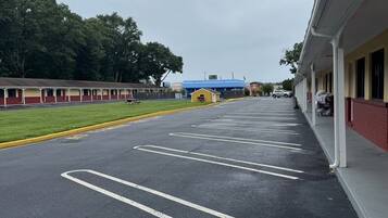 A parking lot with marked spaces, a building with a red and yellow facade, and a blue-roofed structure in the background.