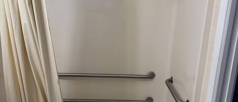 A shower with a glass door, a metal grab bar, and a curtain.