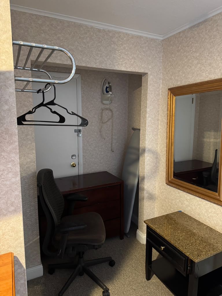 A small office space with a desk, chair, and a mirror.