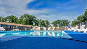 A swimming pool with lounge chairs and a blue deck. - Atlantic Inn & Suites (Belmar)
