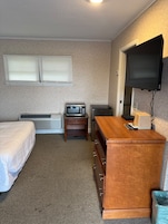 Habitación de hotel con cama, escritorio, televisor y calefacción.