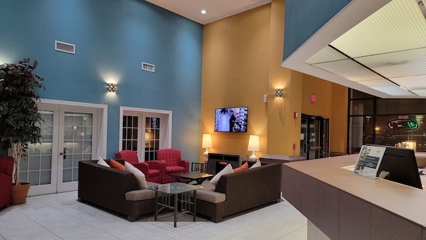 A lobby with a blue and yellow wall, a reception desk, a TV screen, and seating area with red and brown couches.