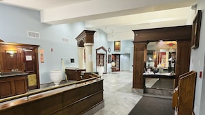 A hotel lobby with a reception desk, a staircase, and a view of the restaurant area. - Town Inn (Bordentown)