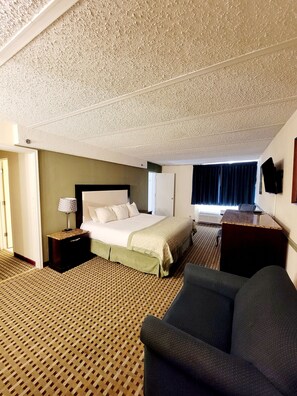 A hotel room with a bed, a desk, a chair, and a patterned carpet. - Town Inn (Bordentown)