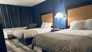 A hotel room with two beds, a nightstand with a lamp, and a wall-mounted phone. - Town Inn (Bordentown)