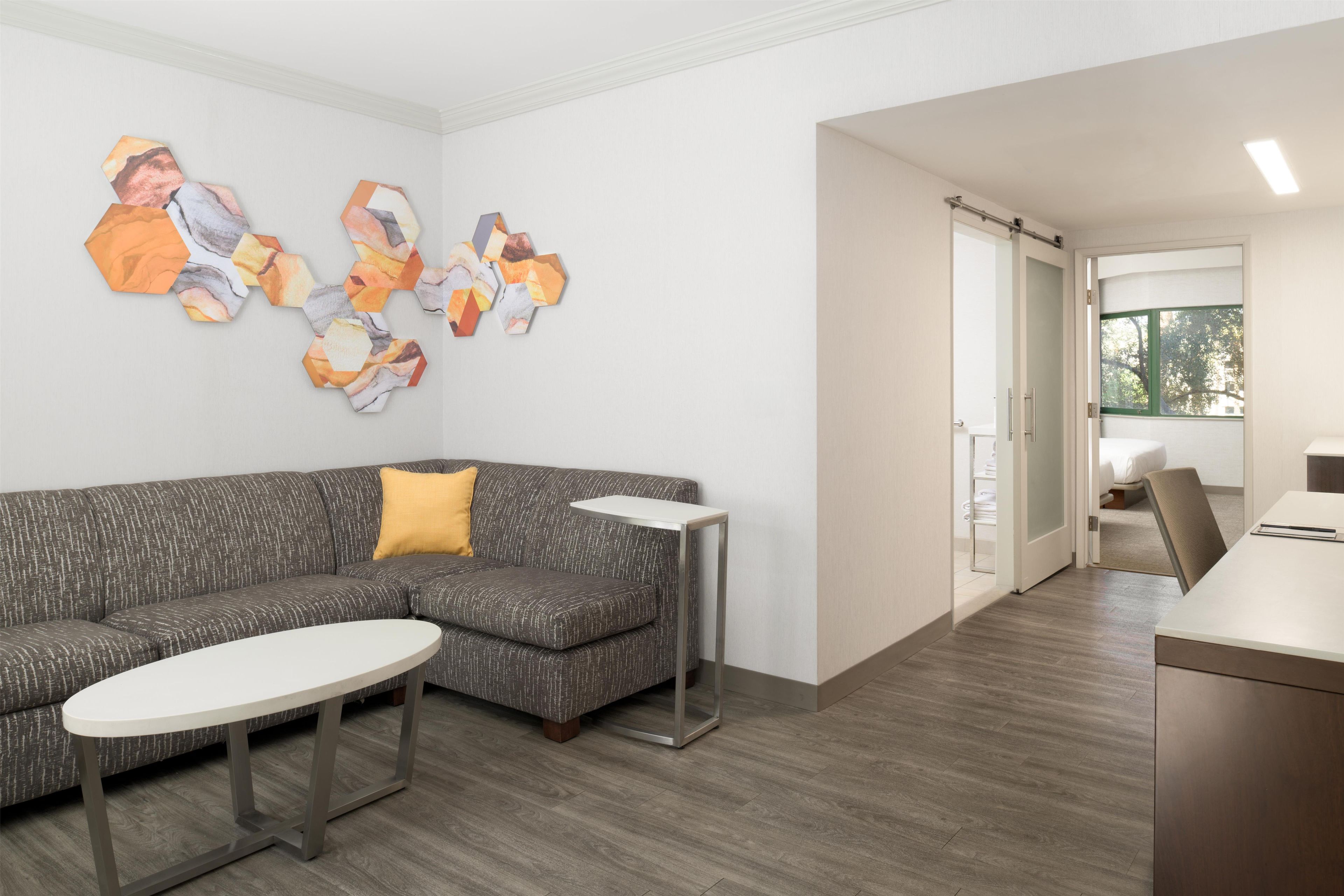 A modern hotel lobby with a grey sectional sofa, a small round table, and a wall art installation.