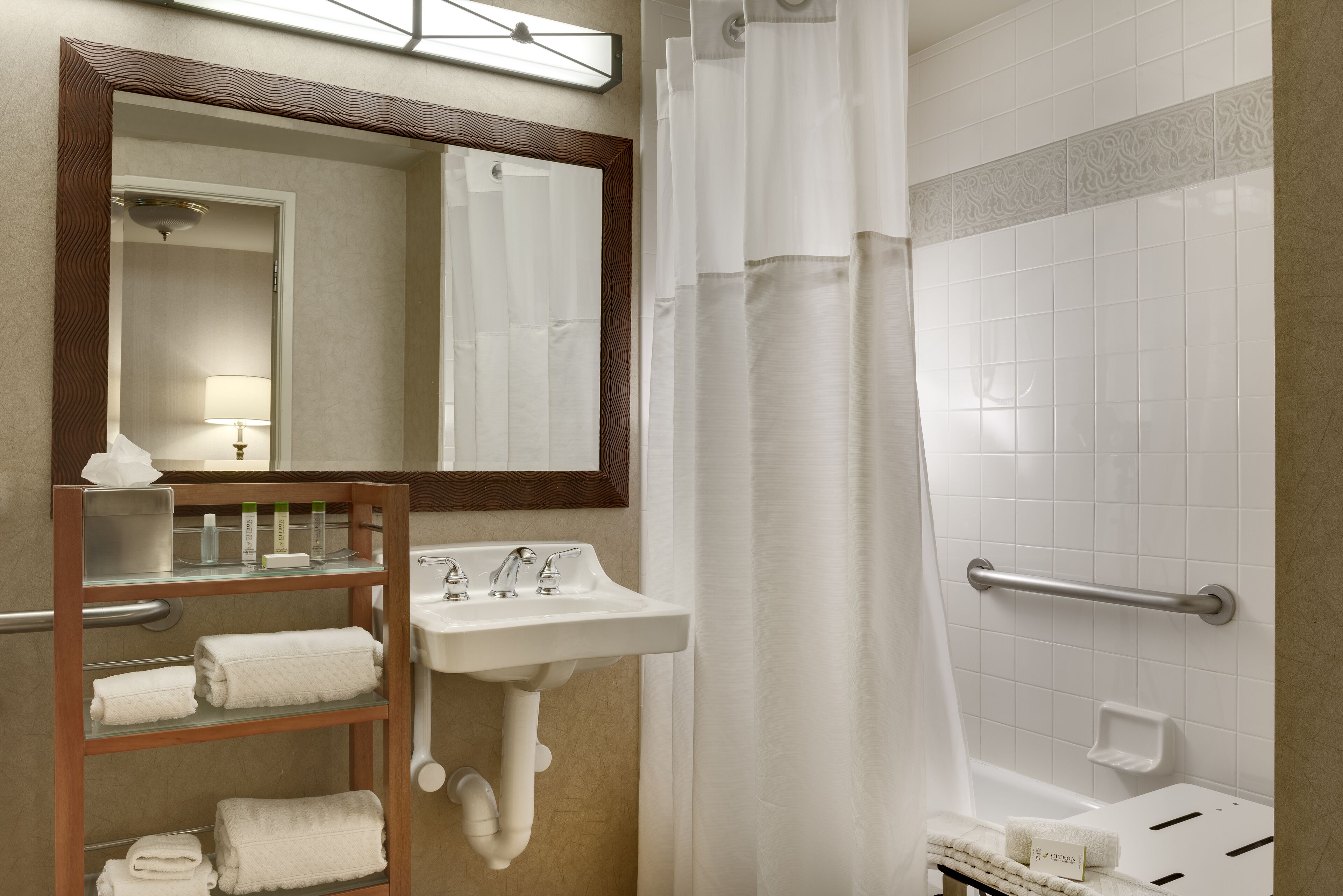 Une salle de bain équipée d’un lavabo, d’un miroir, d’un porte-serviettes et d’une zone douche.